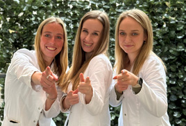 Wir suchen Dich! Drei Mitarbeiterinnen stehen zusammen und zeigen mit dem Finger auf den Betrachter.